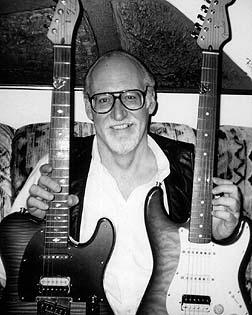 Grayscale photo of a man holding two guitars